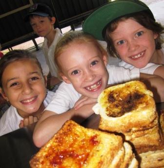 Group of children smiling, pictured behind a stack of toast